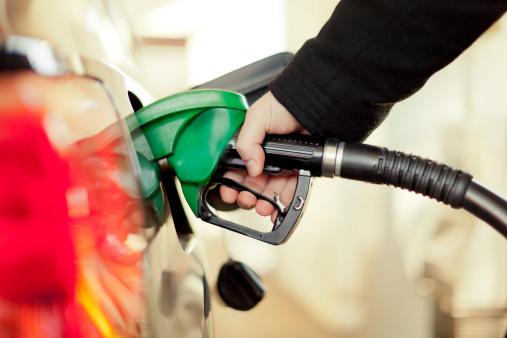 Uma mão coloca a pistola de gasolina no tanque para reabastecer o carro.