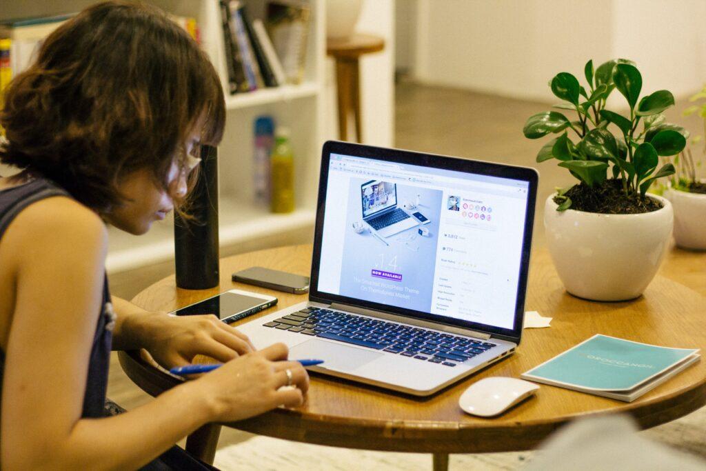 Mulher fazendo anotações com o notebook a frente