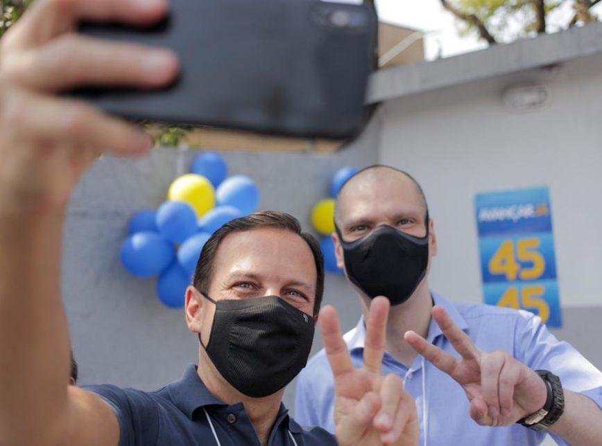 Foto mostra joão dória e bruno covas tirando uma selfie