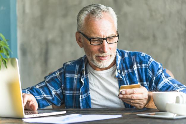 Homem usando cartão de crédito em frente ao notebook