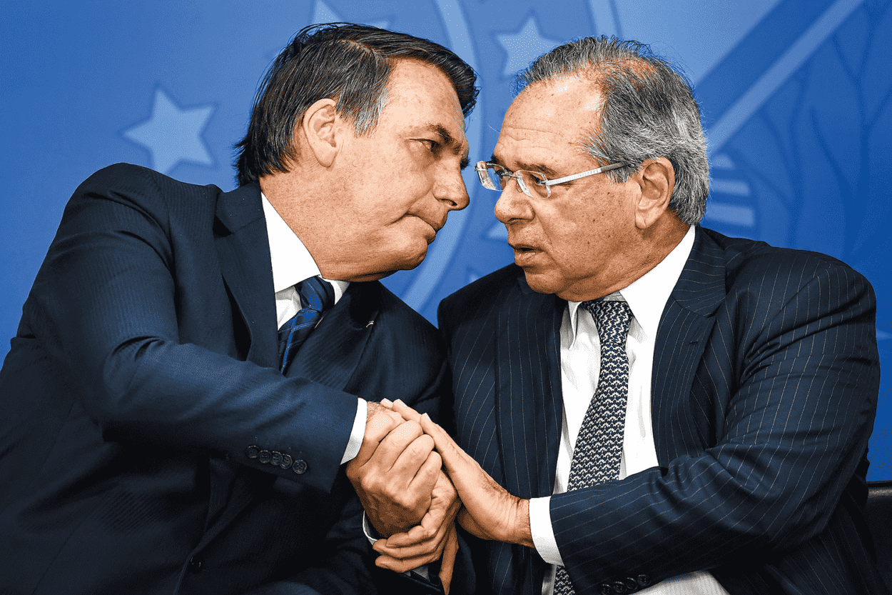 Presidente da República, Jair Bolsonaro à esquerda, e Minsitro da Economia, Paulo Guedes, à direita. Ambos estão ao lado um do outro, e com as mãos dadas