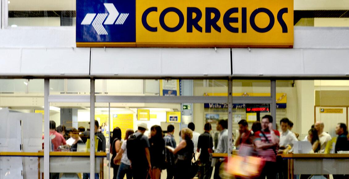 Foto mostra faixada dos Correios com pessoas na entrada