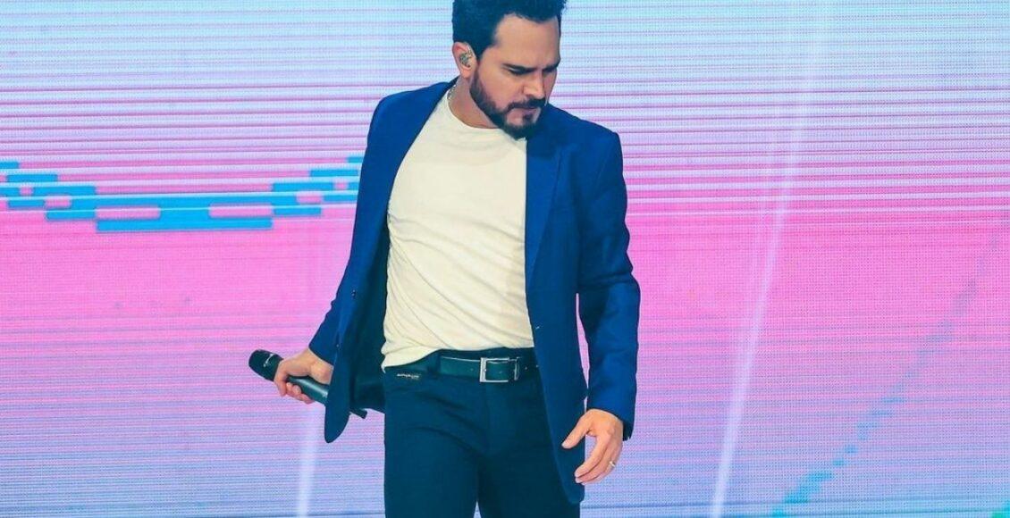 Imagem mostra Luciano Camargo com microfone na mão como cantor gospel