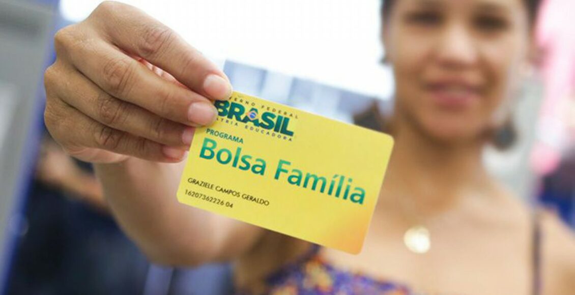 Foto mostra mulher segurando cartão do Bolsa Família