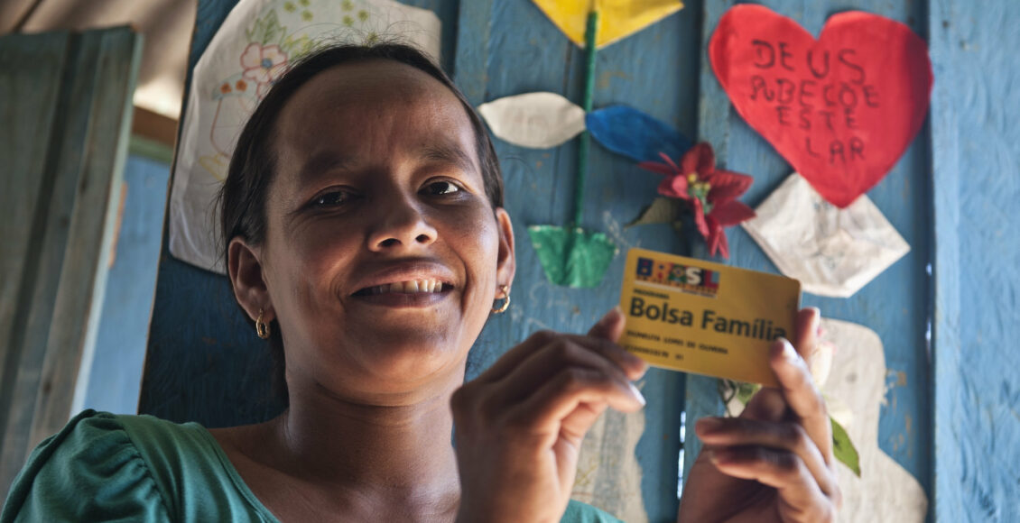 Mulher segurando cartão do Bolsa Família